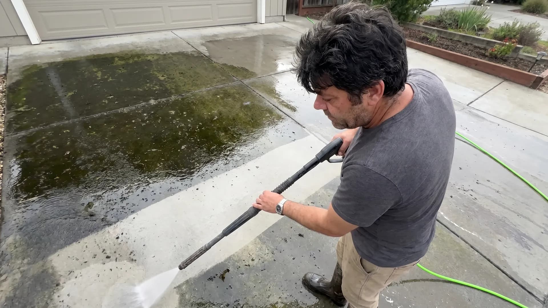 A concrete driveway being surface-cleaned of moss